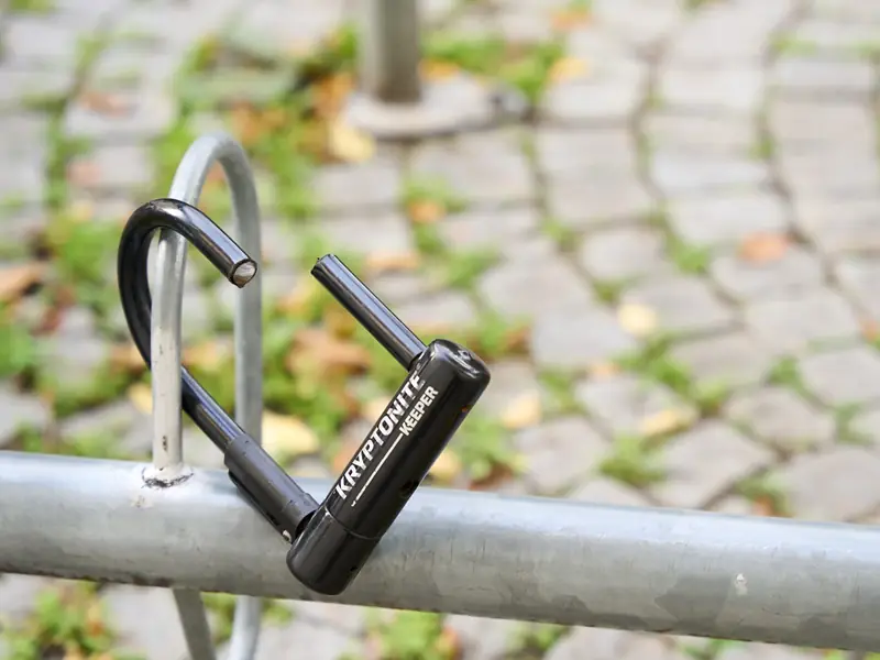 Un antivol en U sectionné pend à un support à vélos vide.