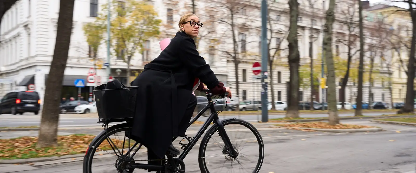 Una ciclista con abrigo negro en el carril bici de la Ringstrasse de Viena