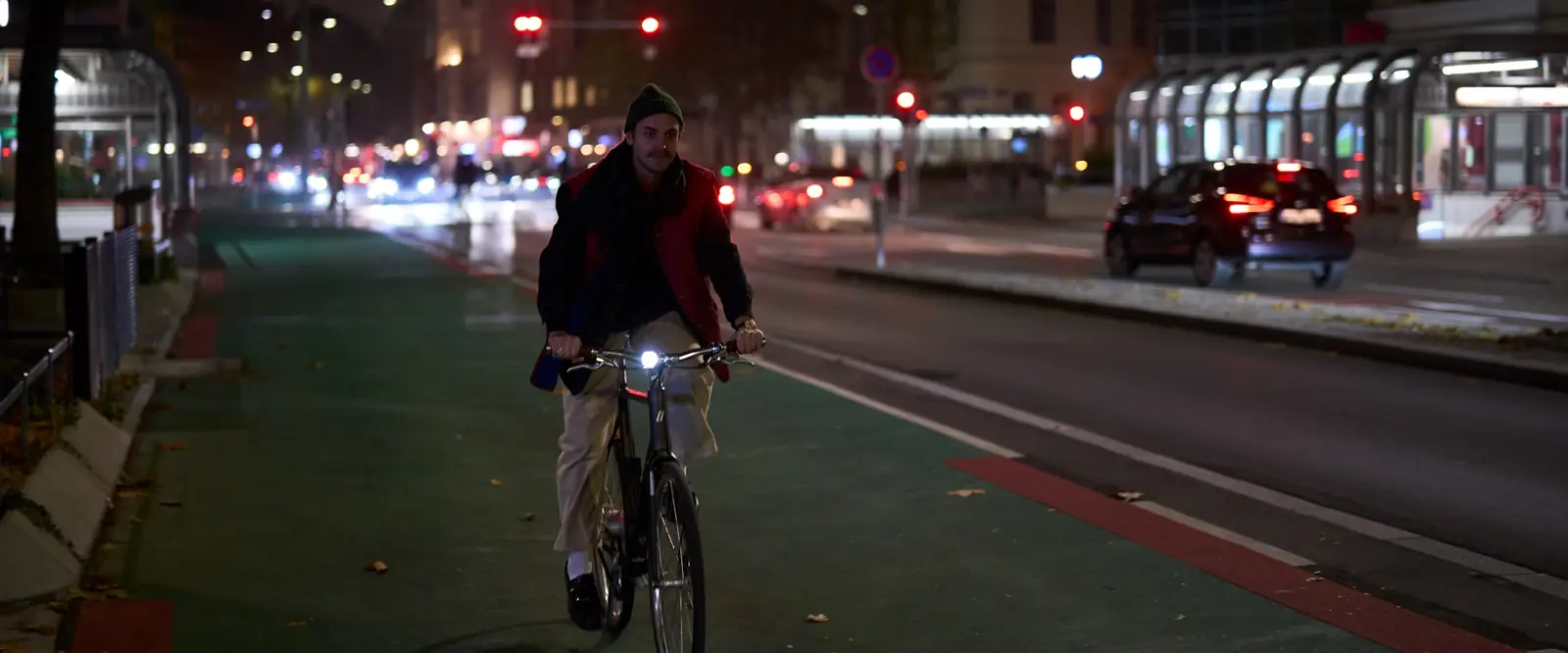 Ein Radfahrer fährt nachts mit eingeschaltetem Vorderlicht auf einem Radweg in Wien