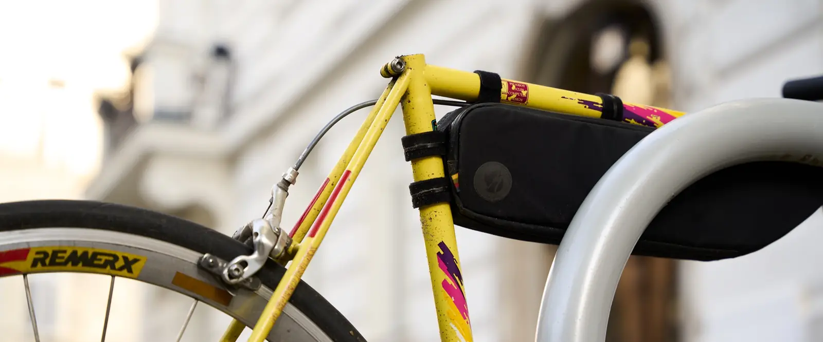 A yellow vintage road bike with painted stripes at a bike rack in Vienna
